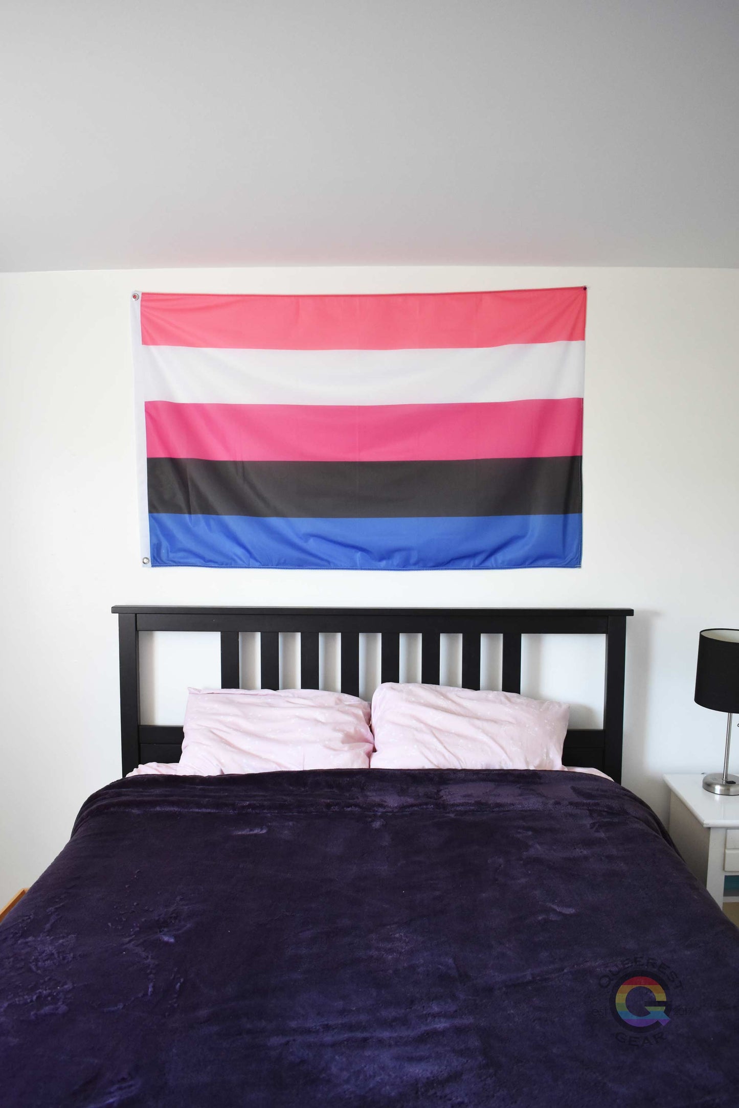  3’x5’ genderfluid pride flag hanging horizontally on the wall of a bedroom centered above a bed with a purple blanket