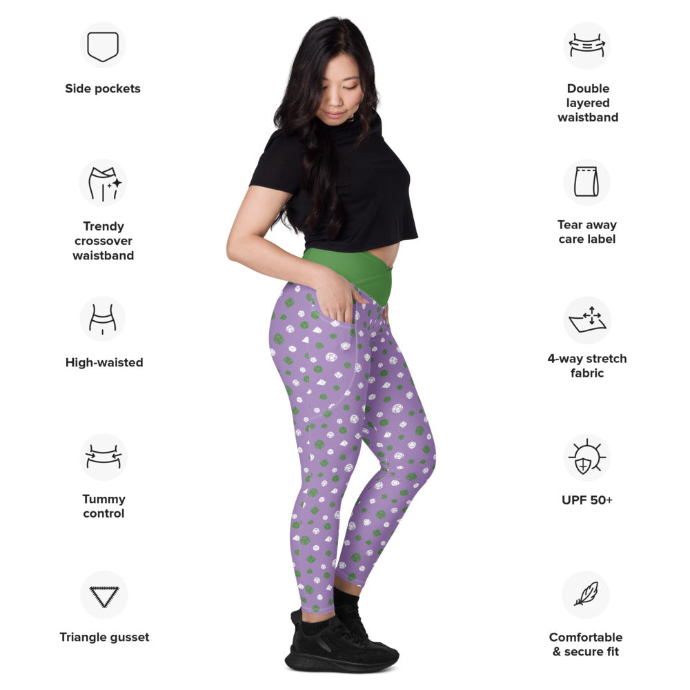 Light-skinned dark-haired female-presenting model wearing the genderqueer dice leggings. she is facing right and has a hand in the pocket. she is surrounded by product specs: "side pockets, trendy crossover waistband, high-waisted, tummy control, triangle gusset, double layered waistband, tear away care label, 4-way stretch fabric, UPF 50+, comfortable & secure fit"