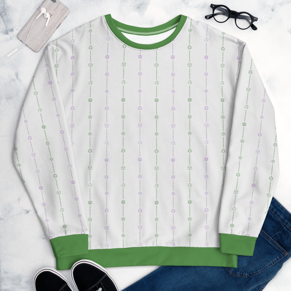 The genderqueer pride sweater laying flat, surrounded by clothes, a phone, and glasses. the sweater is white and has stripes of dashed lines and polyhedral dnd dice in green and purple. The cuffs, collar, and waistband are a matching green