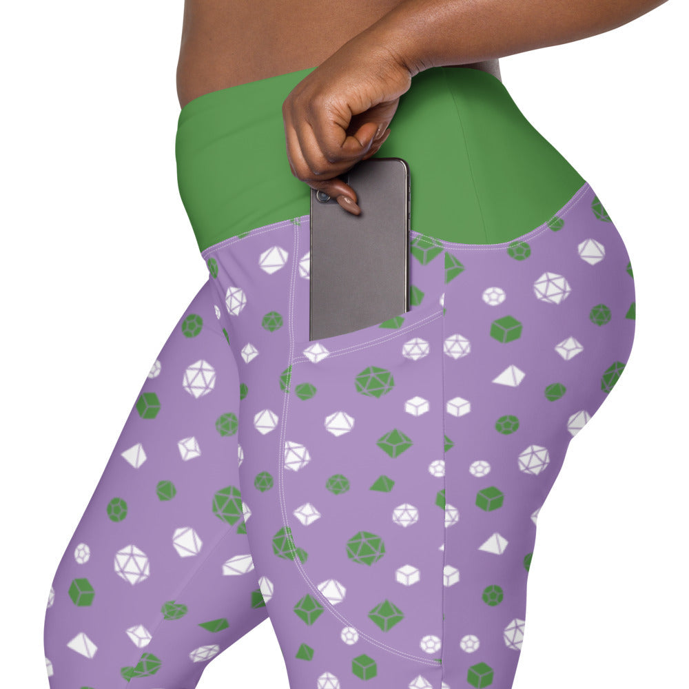 left side view of the genderqueer dnd dice plus size leggings. the dark-skinned female-presenting model is sliding her phone into one of the side pockets