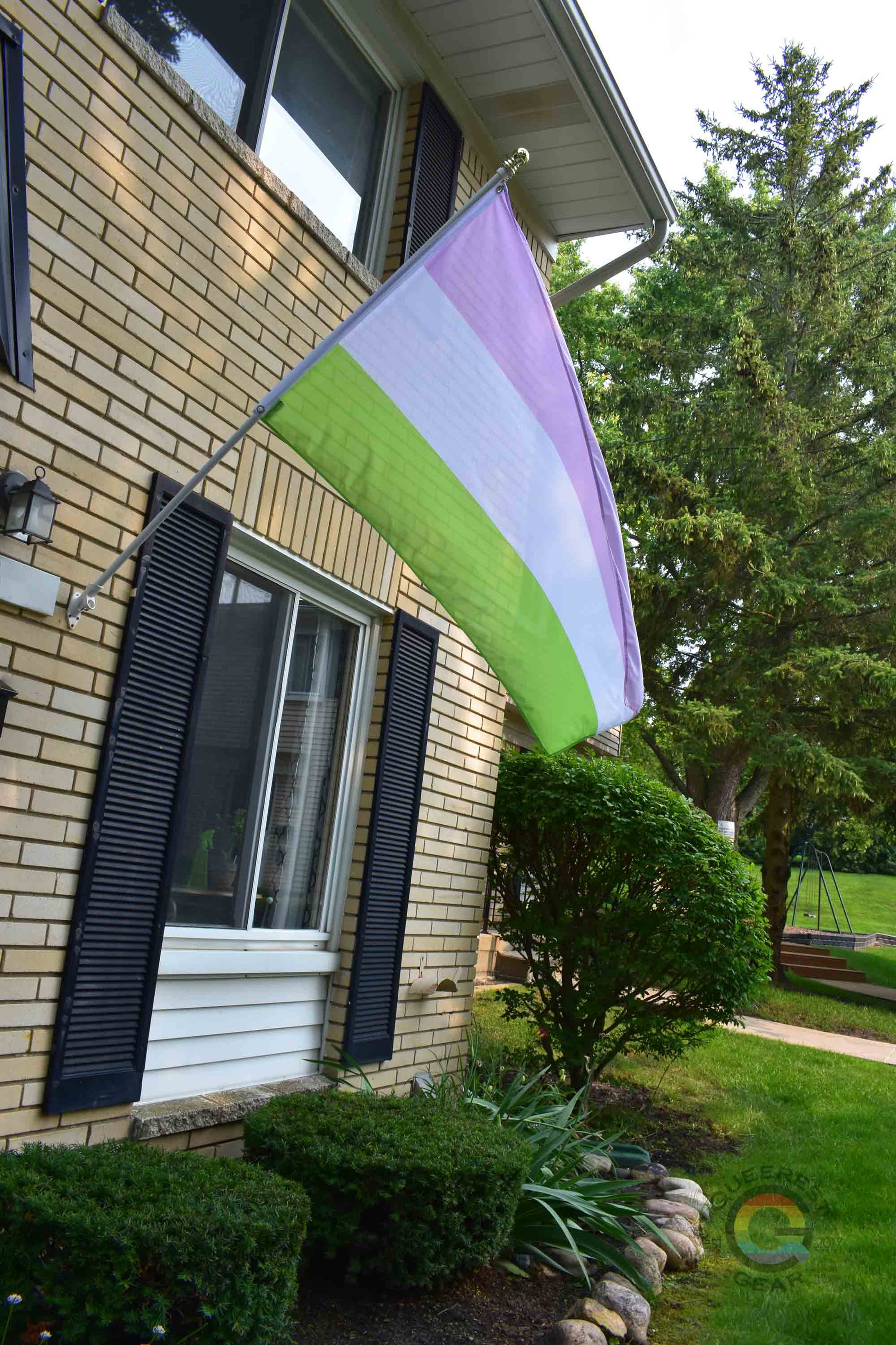 3’x5’ genderqueer pride flag hanging from a flagpole on the outside of a light brick house with dark shutters