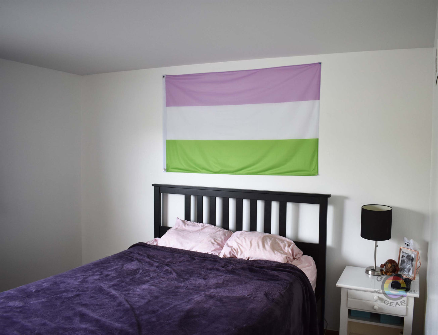 3’x5’ genderqueer pride flag hanging horizontally on the wall of a bedroom centered above a bed with a purple blanket