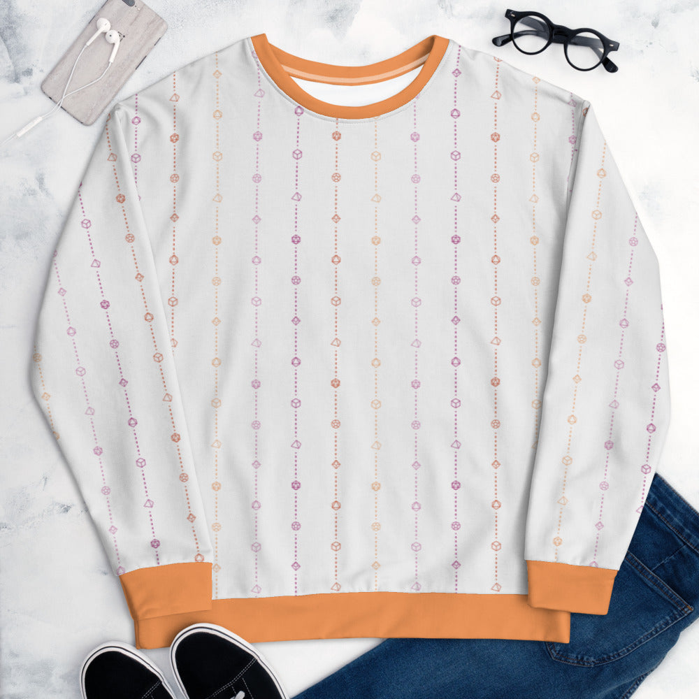 The lesbian pride sweater laying flat, surrounded by clothes, a phone, and glasses. the sweater is white and has stripes of dashed lines and polyhedral dnd dice in pinks and oranges. The cuffs, collar, and waistband are a matching orange