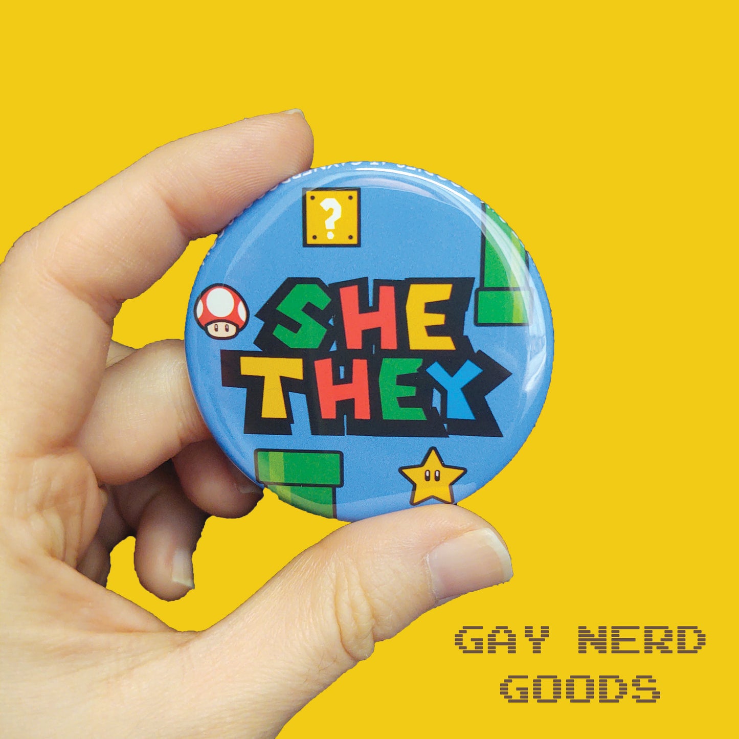 she they mario pronoun button with blue background, green pipes, question block, star, and mushroom held in two fingers