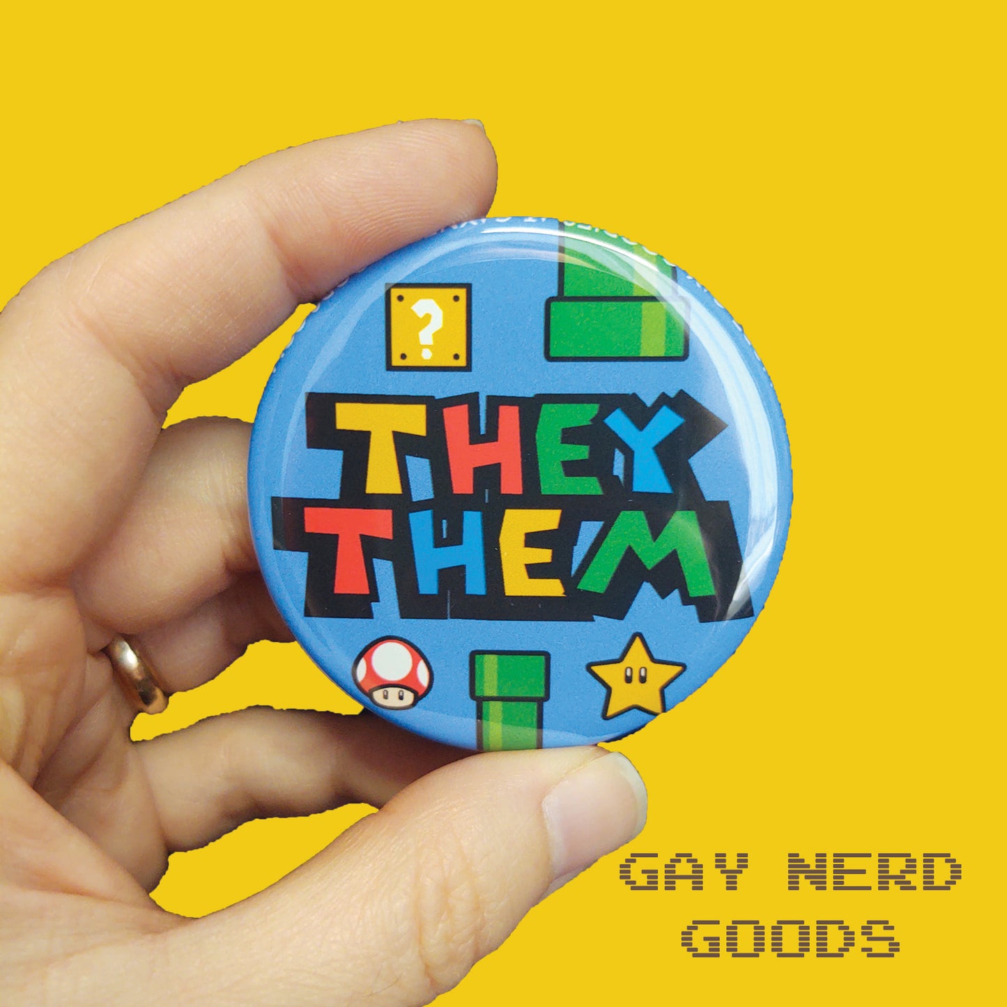 they them mario pronoun button with blue background, green pipes, question block, star, and mushroom held in two fingers