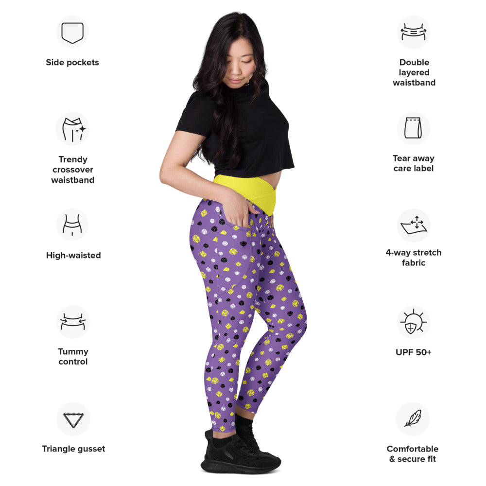 Light-skinned dark-haired female-presenting model wearing nonbinary dice leggings. she is facing right and has a hand in the pocket. she is surrounded by product specs: "side pockets, trendy crossover waistband, high-waisted, tummy control, triangle gusset, double layered waistband, tear away care label, 4-way stretch fabric, UPF 50+, comfortable & secure fit
