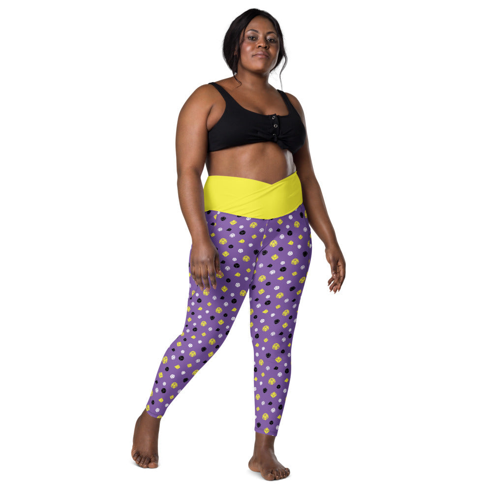 front view of dark-skinned female-presenting plus size model wearing nonbinary dice leggings and a black sports bra. This view shows off the yellow crossover high-rise waistband