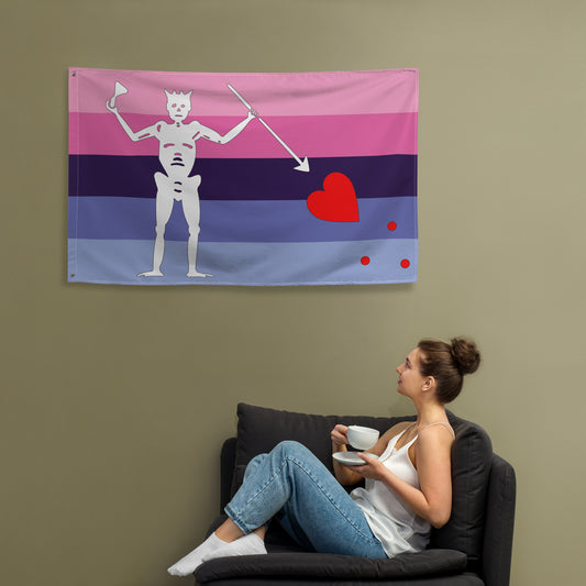 the omnisexual blackbeard pirate flag hanging on a khaki wall above a person sitting in a chair drinking tea