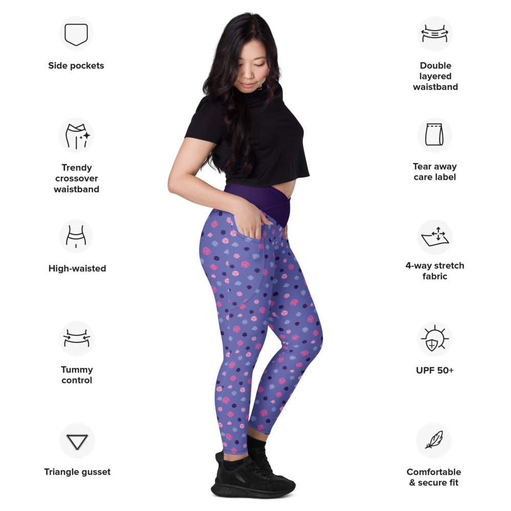 Light-skinned dark-haired female-presenting model wearing omnisexual dice leggings. she is facing right and has a hand in the pocket. she is surrounded by product specs: "side pockets, trendy crossover waistband, high-waisted, tummy control, triangle gusset, double layered waistband, tear away care label, 4-way stretch fabric, UPF 50+, comfortable & secure fi