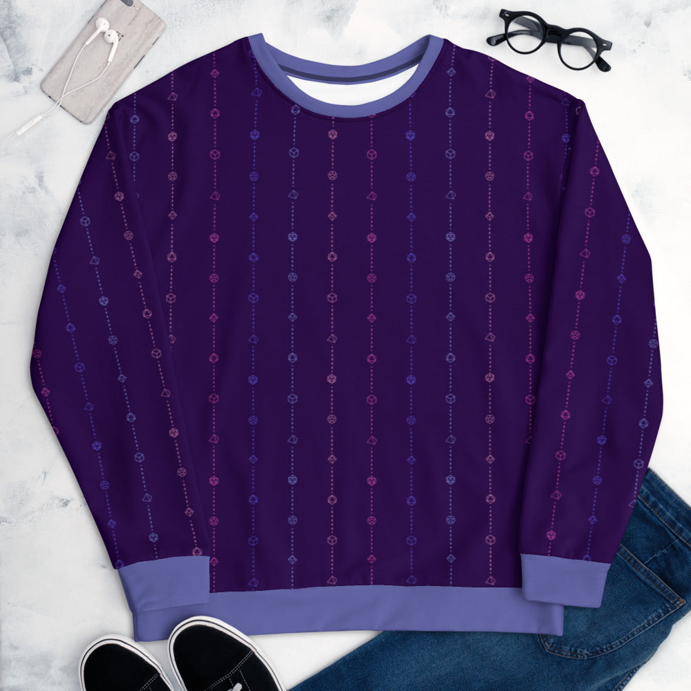 The omnisexual pride sweater laying flat, surrounded by clothes, a phone, and glasses. the sweater is dark purple and has stripes of dashed lines and polyhedral dnd dice in pinks and blues. The cuffs, collar, and waistband are a matching blue
