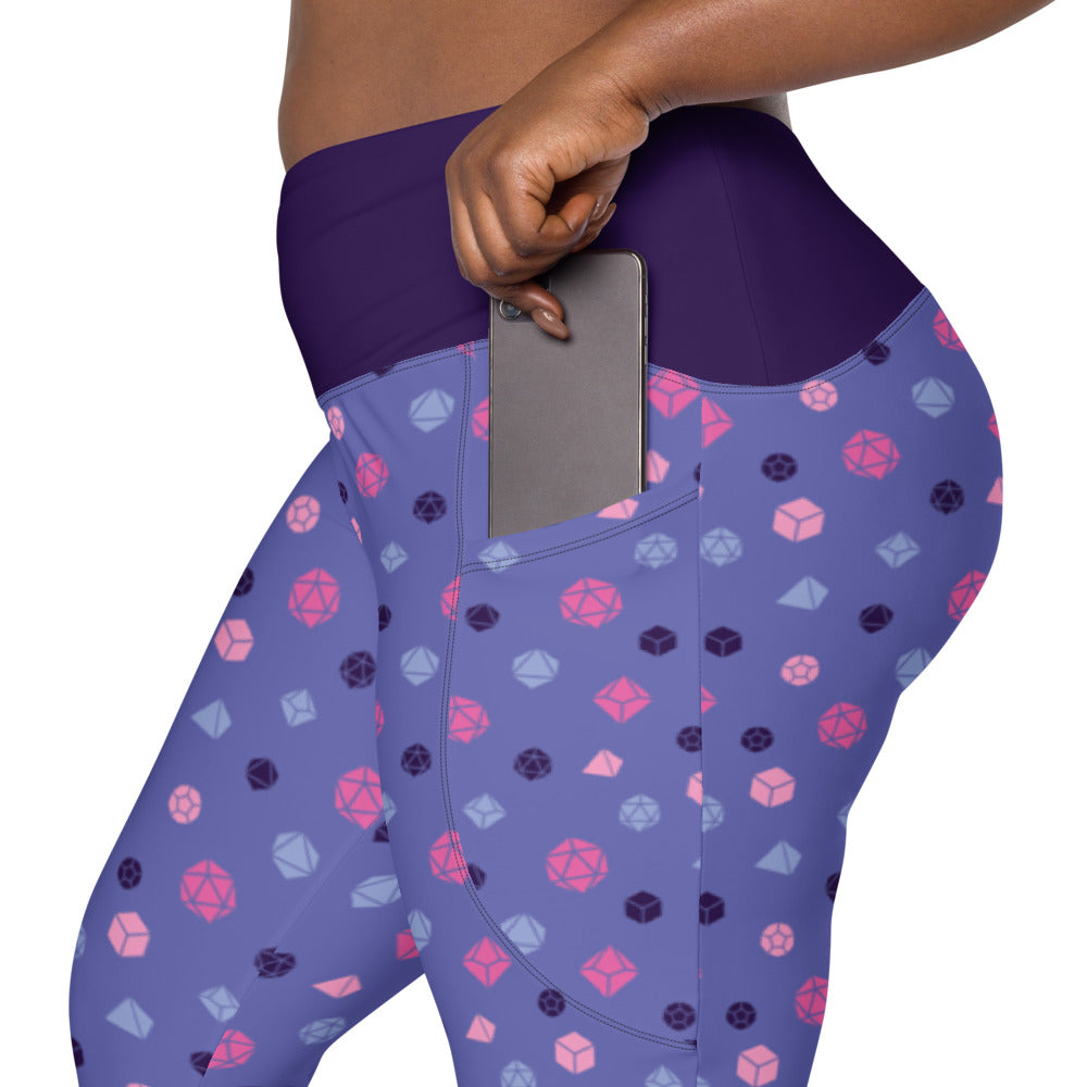 left side view of omnisexual dnd dice plus size leggings. the dark-skinned female-presenting model is sliding her phone into one of the side pockets