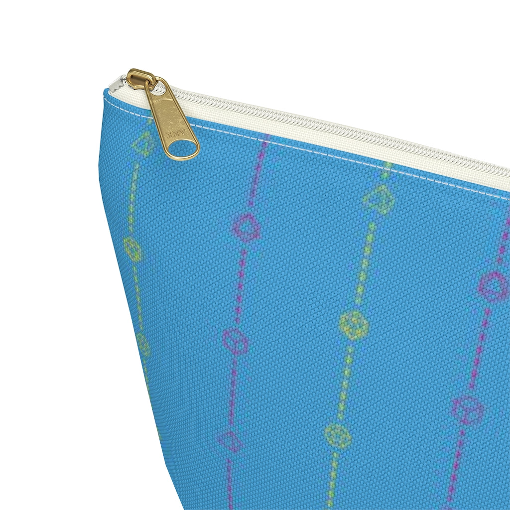 the large pansexual dice t-bottom pouch  corner detail on a white background. it's blue with pink and yellow stripes of dashed lines and polyhedral dice and a gold zipper pull