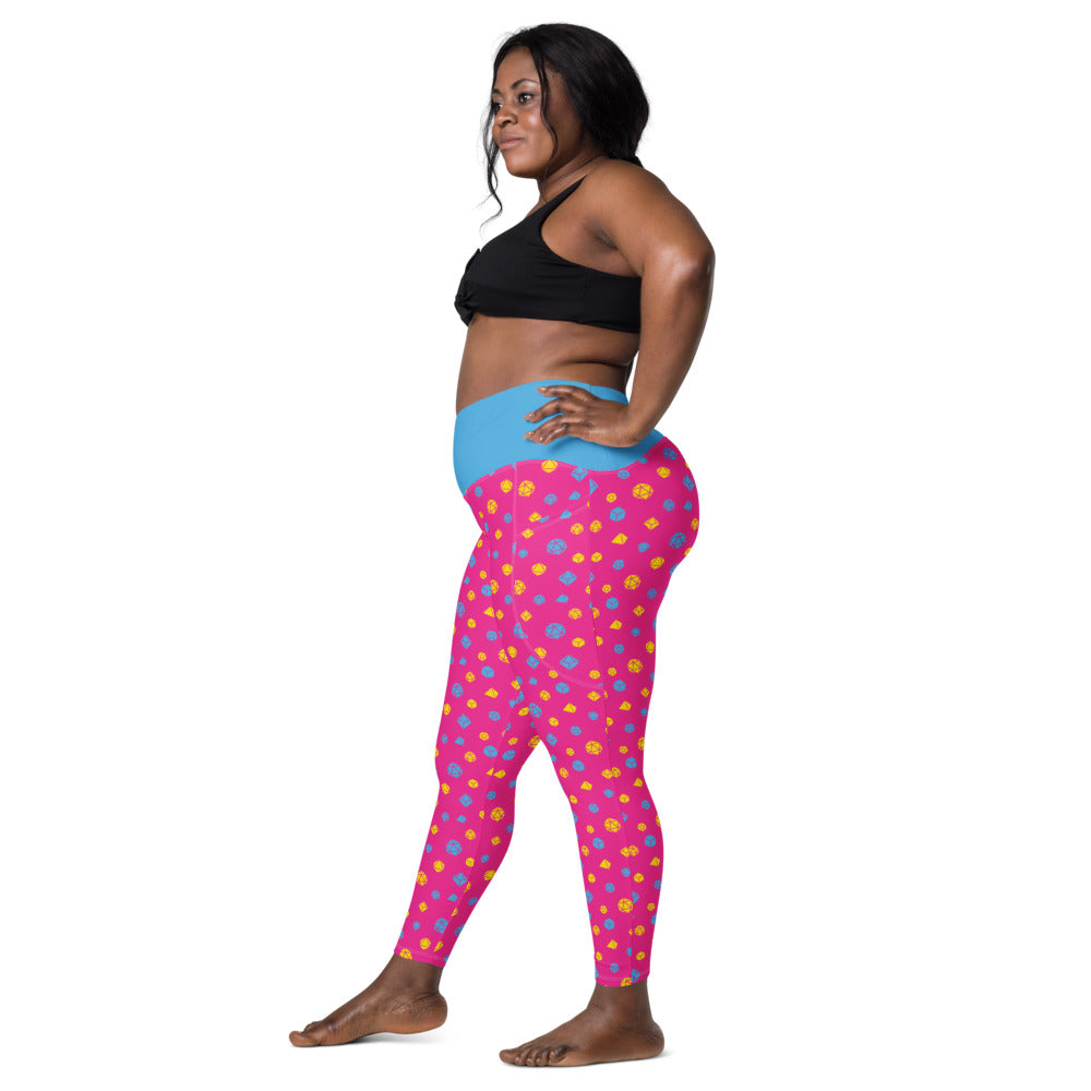 Left side view of dark-skinned female-presenting model wearing the pansexual dice leggings and black sports bra. She is facing left with her left hand on her hip and right leg forward