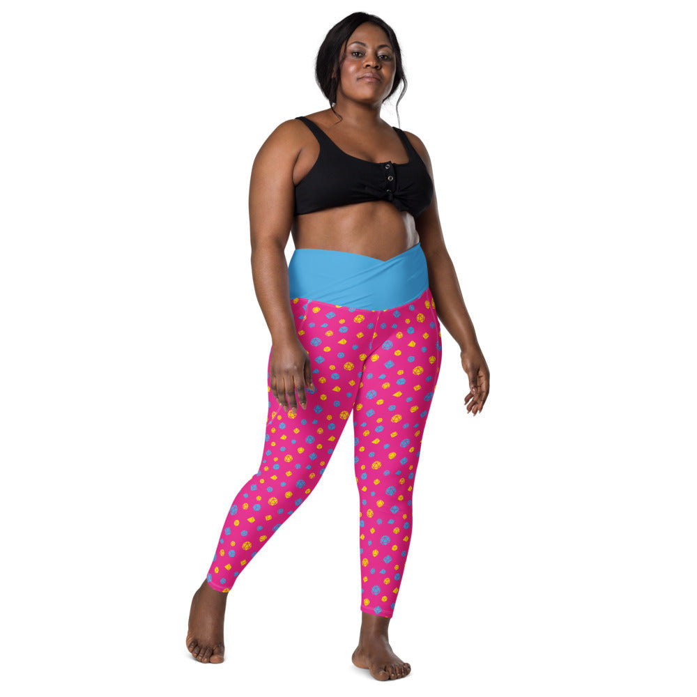 front view of dark-skinned female-presenting plus size model wearing pansexual dice leggings and a black sports bra. This view shows off the blue crossover high-rise waistband