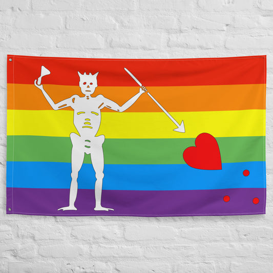 the rainbow blackbeard pirate flag hanging on a white brick background
