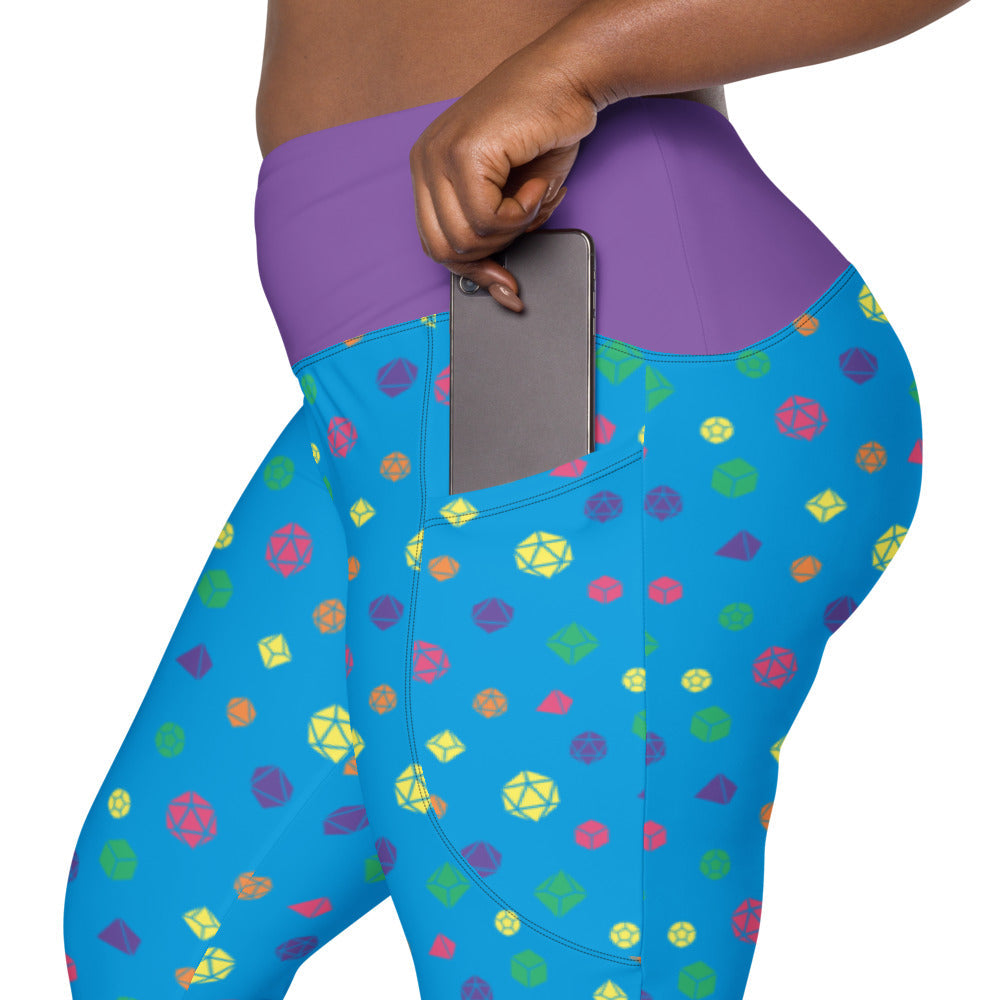 left side view of rainbow dnd dice plus size leggings. the dark-skinned female-presenting model is sliding her phone into one of the side pockets