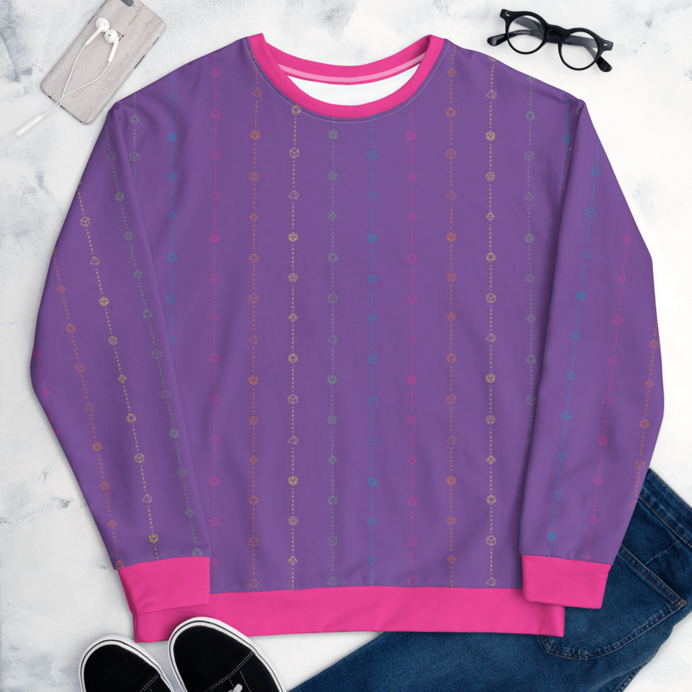 The rainbow pride sweater laying flat, surrounded by clothes, a phone, and glasses. the sweater is purple and has stripes of dashed lines and polyhedral dnd dice in pink, orange, yellow, green, and blue. The cuffs, collar, and waistband are a matching pink