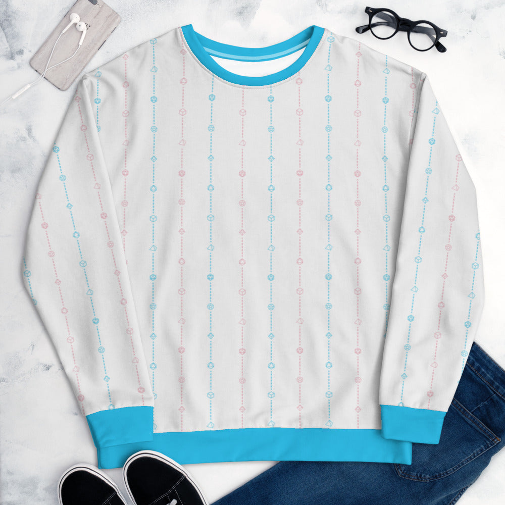 The transgender pride sweater laying flat, surrounded by clothes, a phone, and glasses. the sweater is white and has stripes of dashed lines and polyhedral dnd dice in pink and blue. The cuffs, collar, and waistband are a matching blue